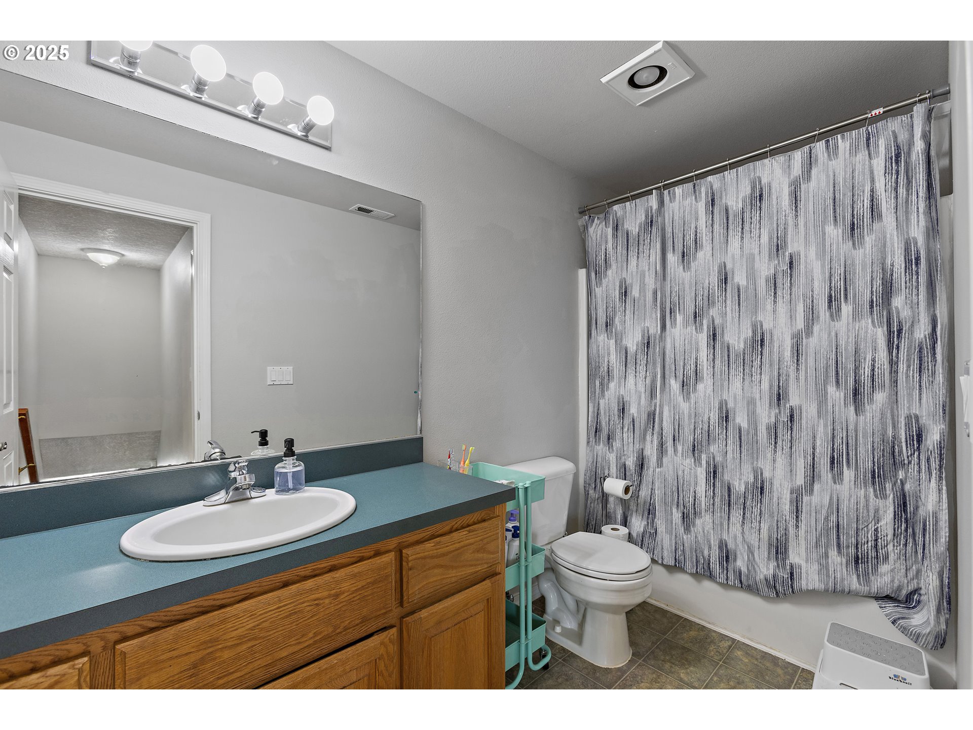7771 St Charles Street Northeast Keizer, OR 97303 - Photo 23 of 42 a bathroom with a granite countertop sink toilet a mirror and shower curtain