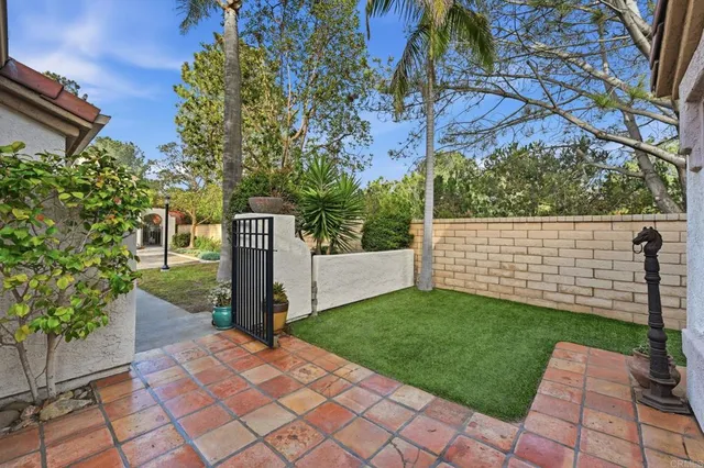 a view of a backyard with brick wall and potted plants