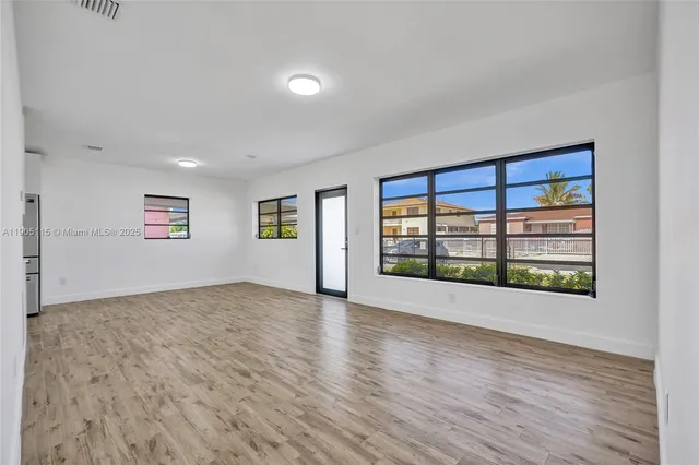 a view of an empty room with a window and wooden floor
