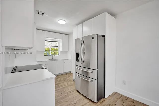 a kitchen with a refrigerator and a stove top oven