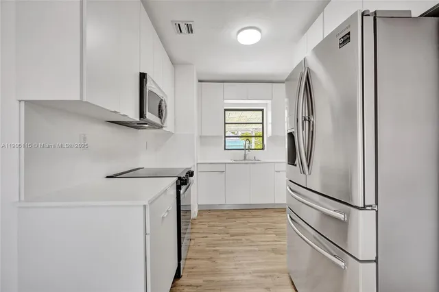 a kitchen with stainless steel appliances a refrigerator and a window