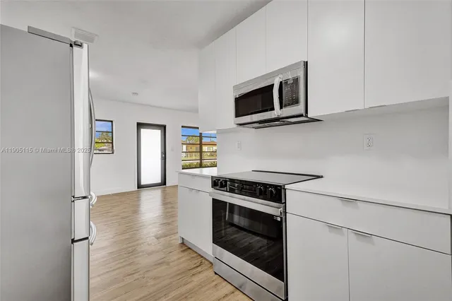 a kitchen with stainless steel appliances white cabinets and wooden floor
