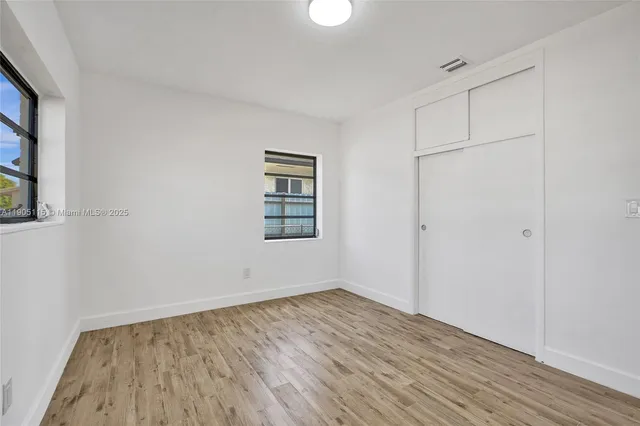 an empty room with wooden floor and closet