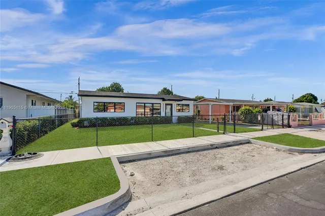 a view of a brick house next to a yard with big trees