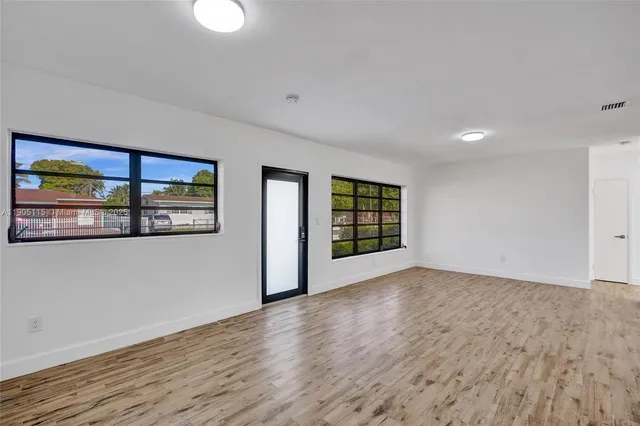 a view of an empty room with a window and wooden floor