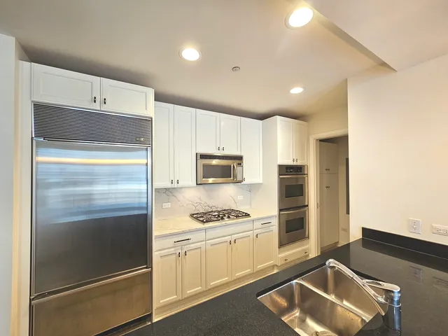 a kitchen with white cabinets and stainless steel appliances