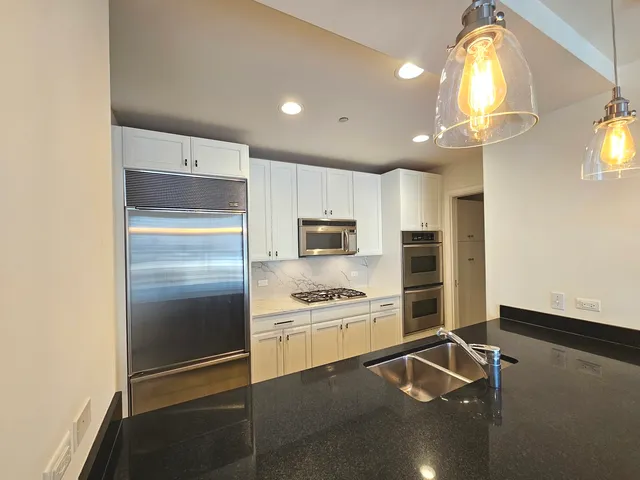 a kitchen with kitchen island white cabinets and stainless steel appliances