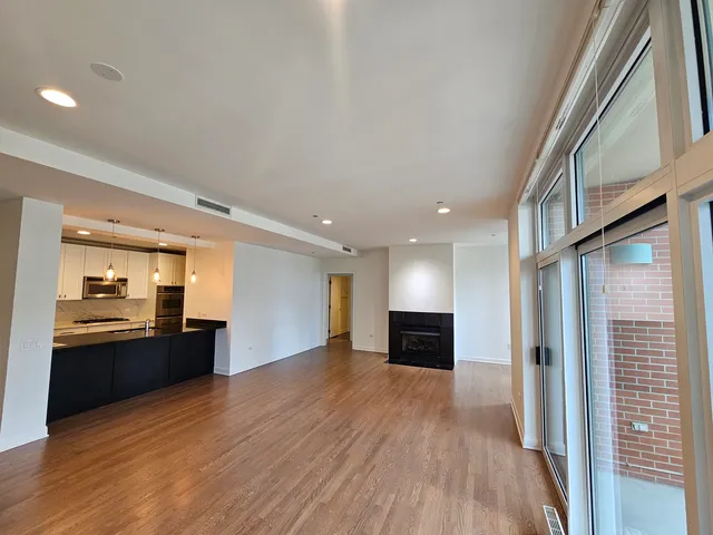 a view of a big room with wooden floor and a kitchen