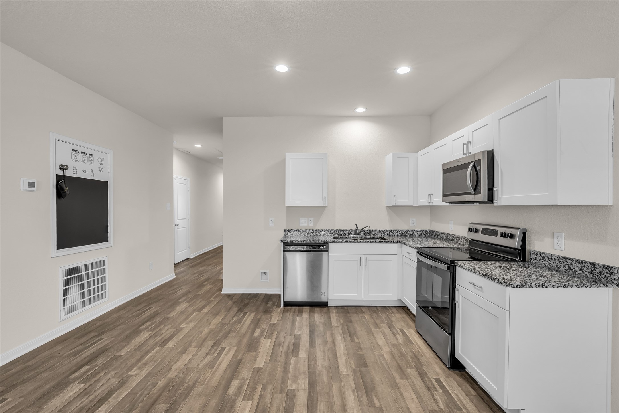 2511 17th Street Hempstead, TX 77445 - Photo 5 of 23 a large kitchen with granite countertop a stove top oven a sink dishwasher and a refrigerator with wooden floor