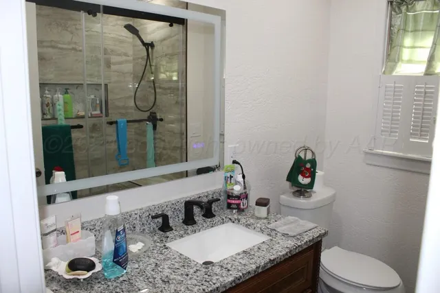 a bathroom with a granite countertop sink a toilet and shower
