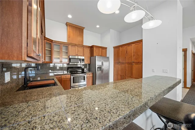 a kitchen with stainless steel appliances granite countertop a stove refrigerator and cabinets