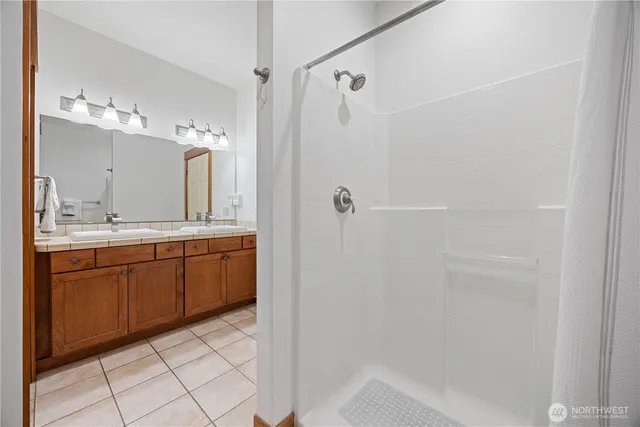 a spacious bathroom with a double vanity sink a mirror and a bathtub