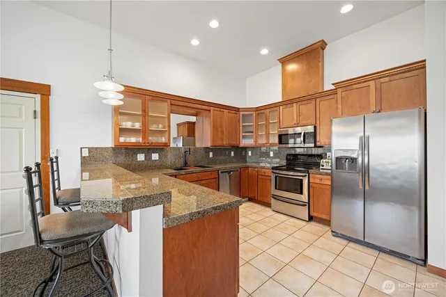 a kitchen with stainless steel appliances granite countertop a refrigerator a stove a sink a dining table and chairs
