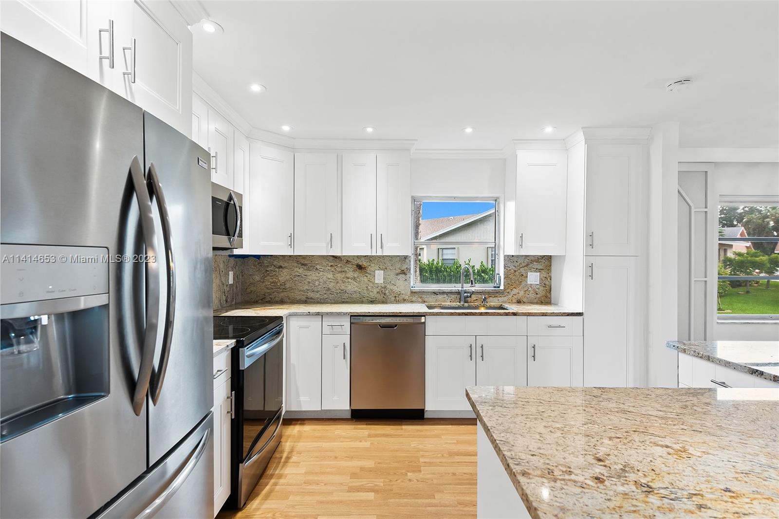 6240 Dusenburg Road Delray Beach, FL 33484 - Photo 13 of 25 a kitchen with stainless steel appliances granite countertop a refrigerator a sink dishwasher a stove and white countertops with wooden floor
