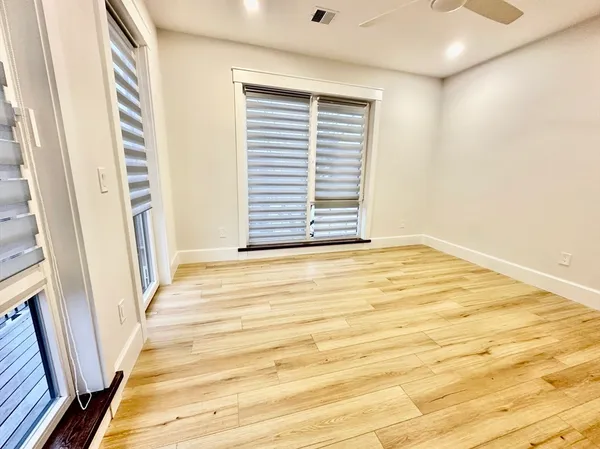 a view of an empty room with wooden floor and a window