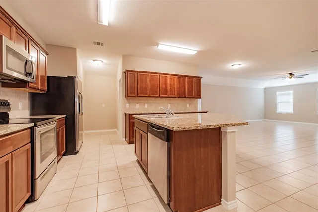 a kitchen with stainless steel appliances granite countertop a stove a sink and a refrigerator