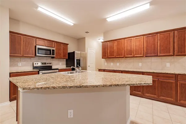 a kitchen with granite countertop wooden cabinets a refrigerator and a sink