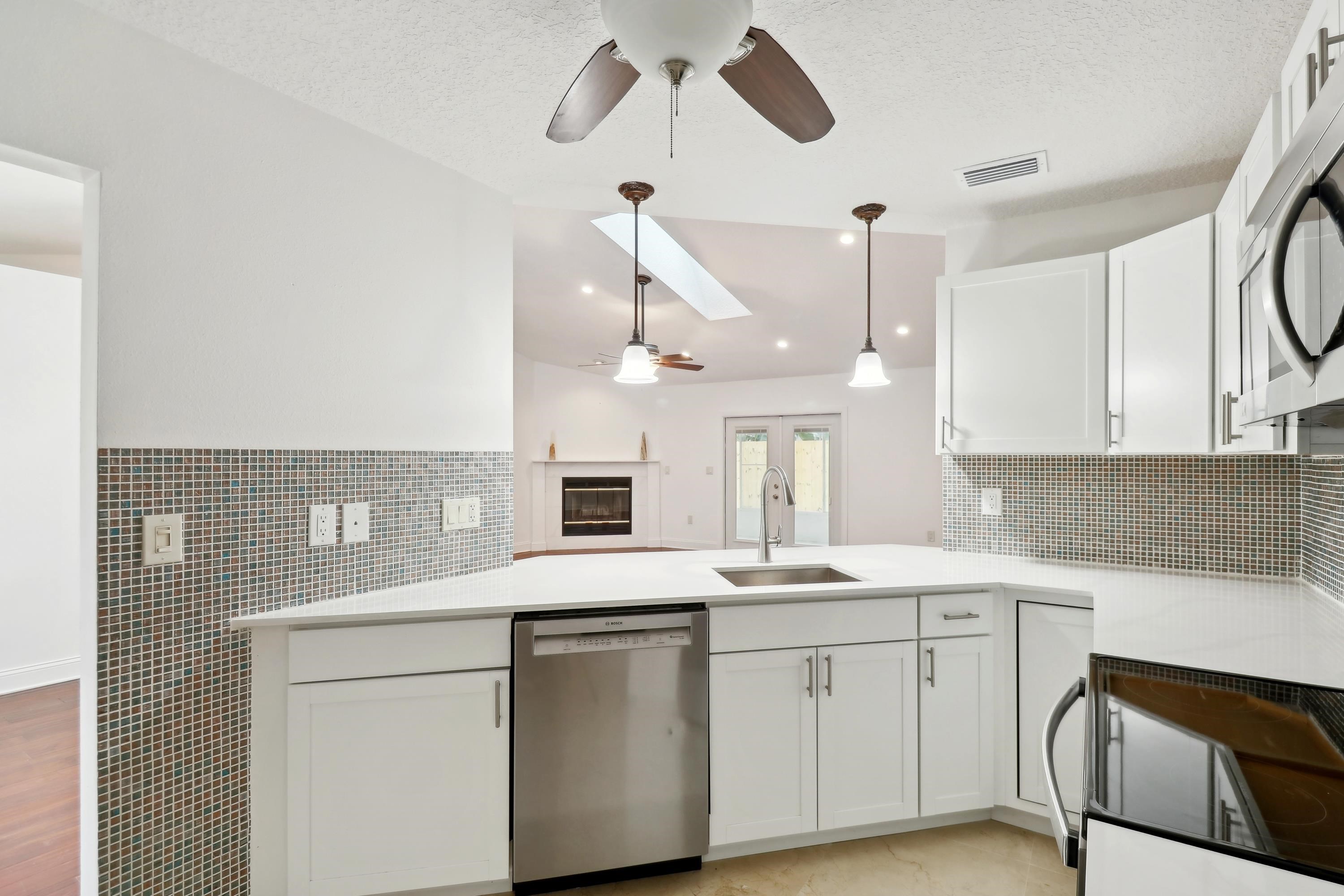 240 Jasmine Road St. Augustine, FL 32086 - Photo 13 of 30 a kitchen with a sink dishwasher and white cabinets with wooden floor