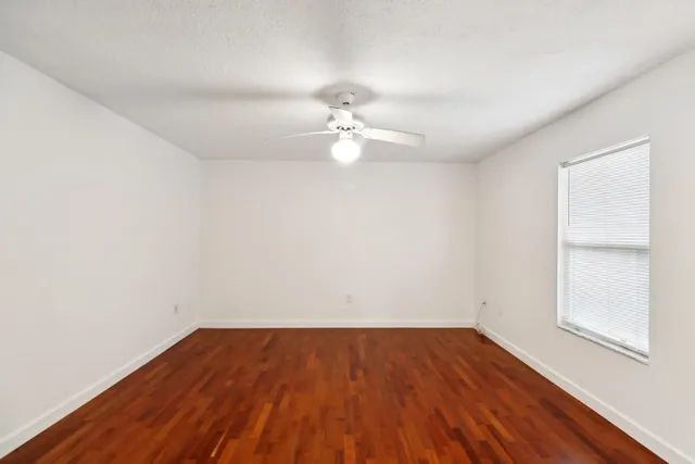 a view of a room with wooden floor and a ceiling fan