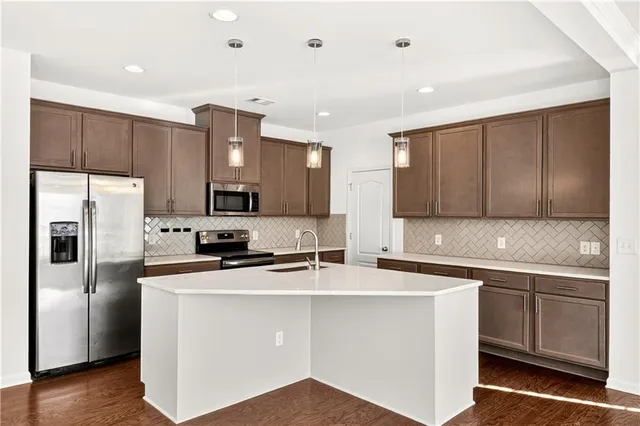 a kitchen with stainless steel appliances a sink stove refrigerator and cabinets