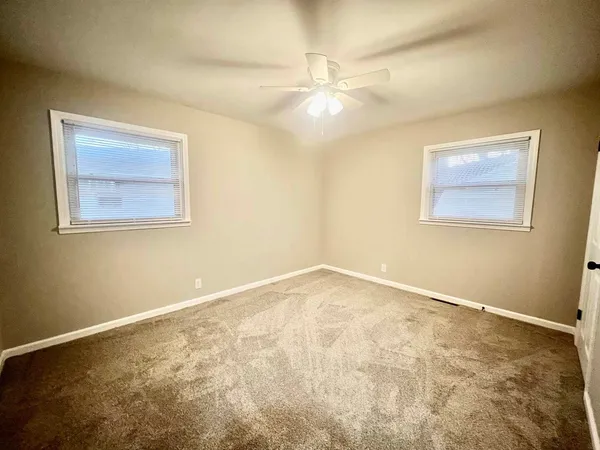 a view of an empty room with a chandelier fan