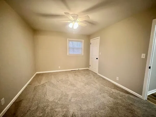 an empty room with a chandelier fan and windows