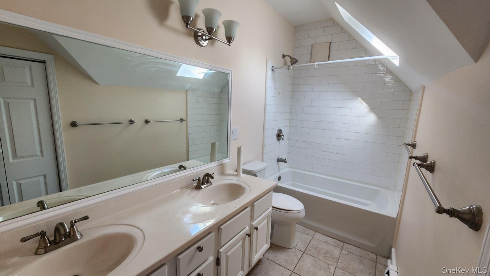 92 Roe Avenue, Unit 3 Highland Falls, NY 10928 - Photo 14 of 17 Bathroom featuring a dual vanity with integrated sinks, a built-in tub with subway tile surround, a skylight, and chrome fixtures