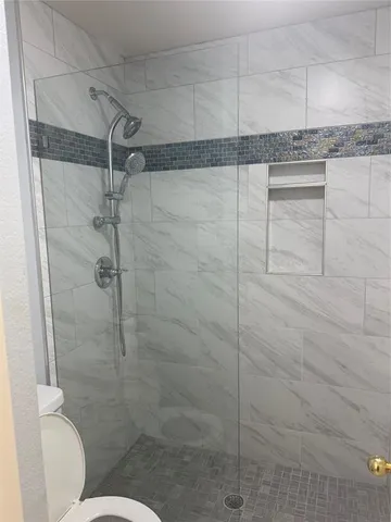 a bathroom with a granite countertop shower and a toilet