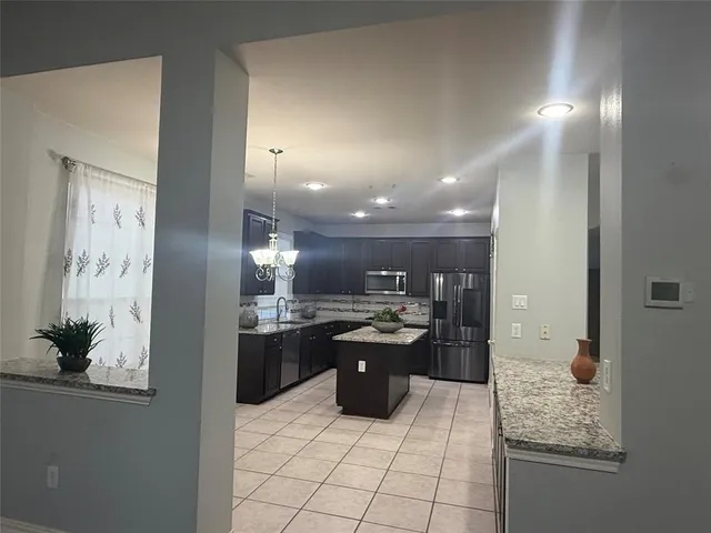 a kitchen with stainless steel appliances kitchen island granite countertop a refrigerator and a sink