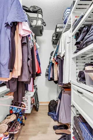 a view of walk in closet with clothes and shoes