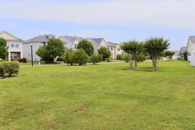 a backyard of a house with lots of green space and lake view in back
