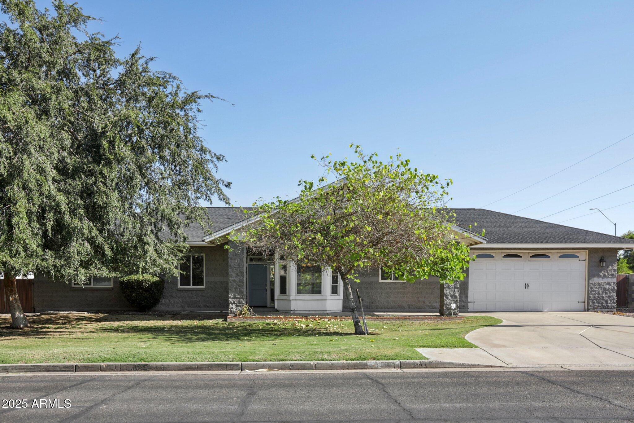 702 West Why Worry Lane Phoenix, AZ 85021 - Photo 1 of 46 a front view of a house with a garden and trees