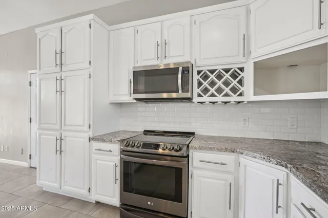 a view of kitchen with stainless steel appliances granite countertop cabinets and window