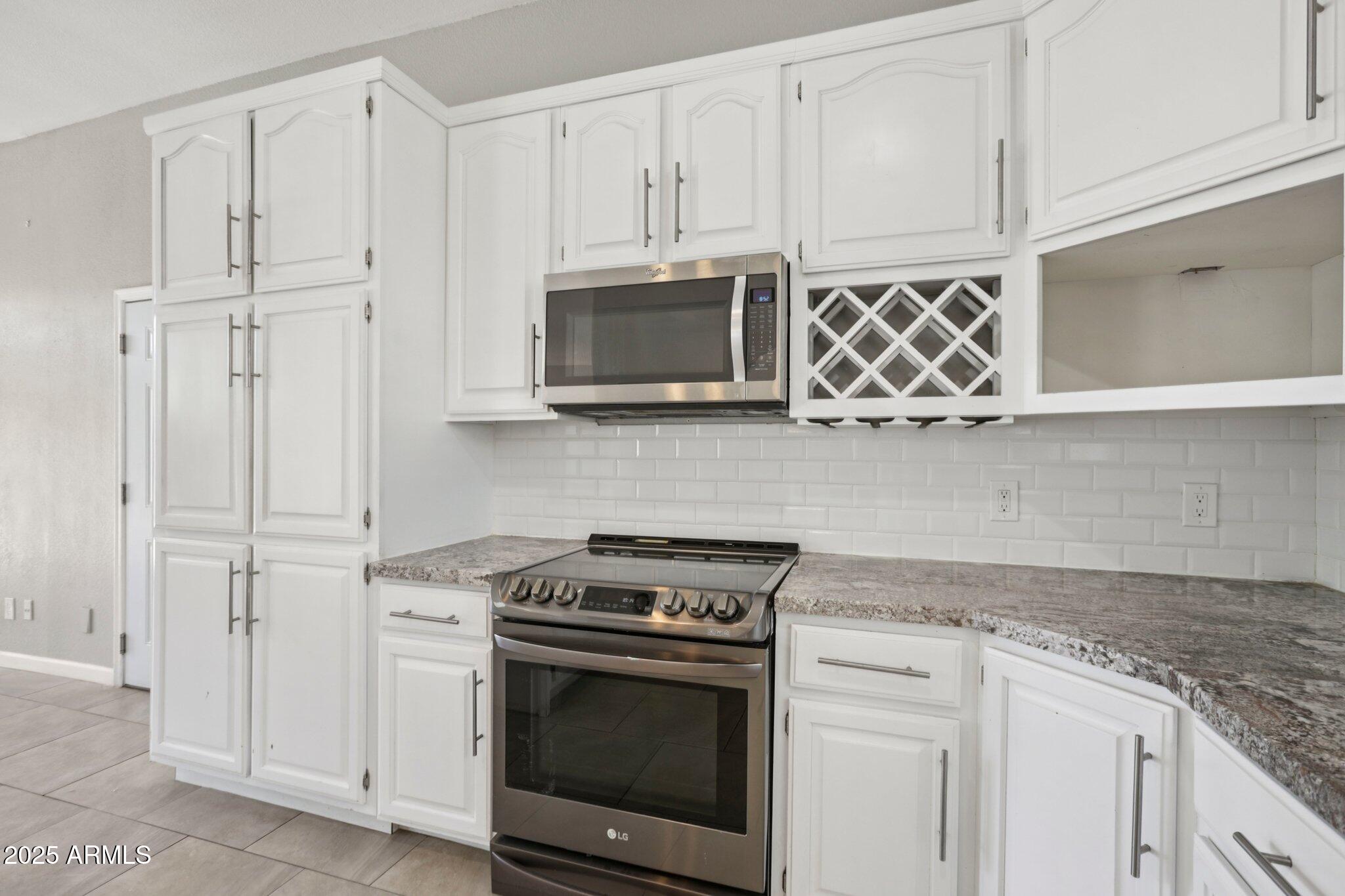 702 West Why Worry Lane Phoenix, AZ 85021 - Photo 9 of 46 a kitchen with stainless steel appliances granite countertop white cabinets and a stove top oven