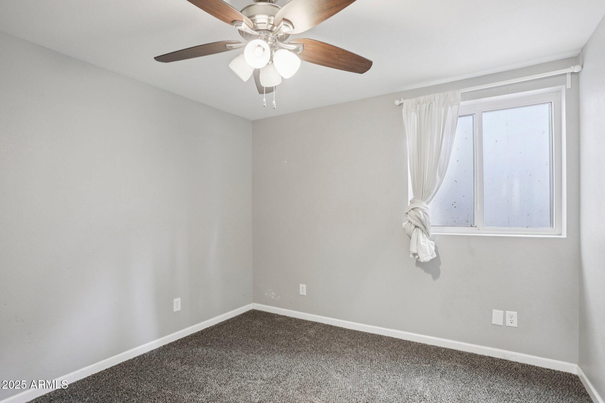702 West Why Worry Lane Phoenix, AZ 85021 - Photo 33 of 46 an empty room with a chandelier fan and windows