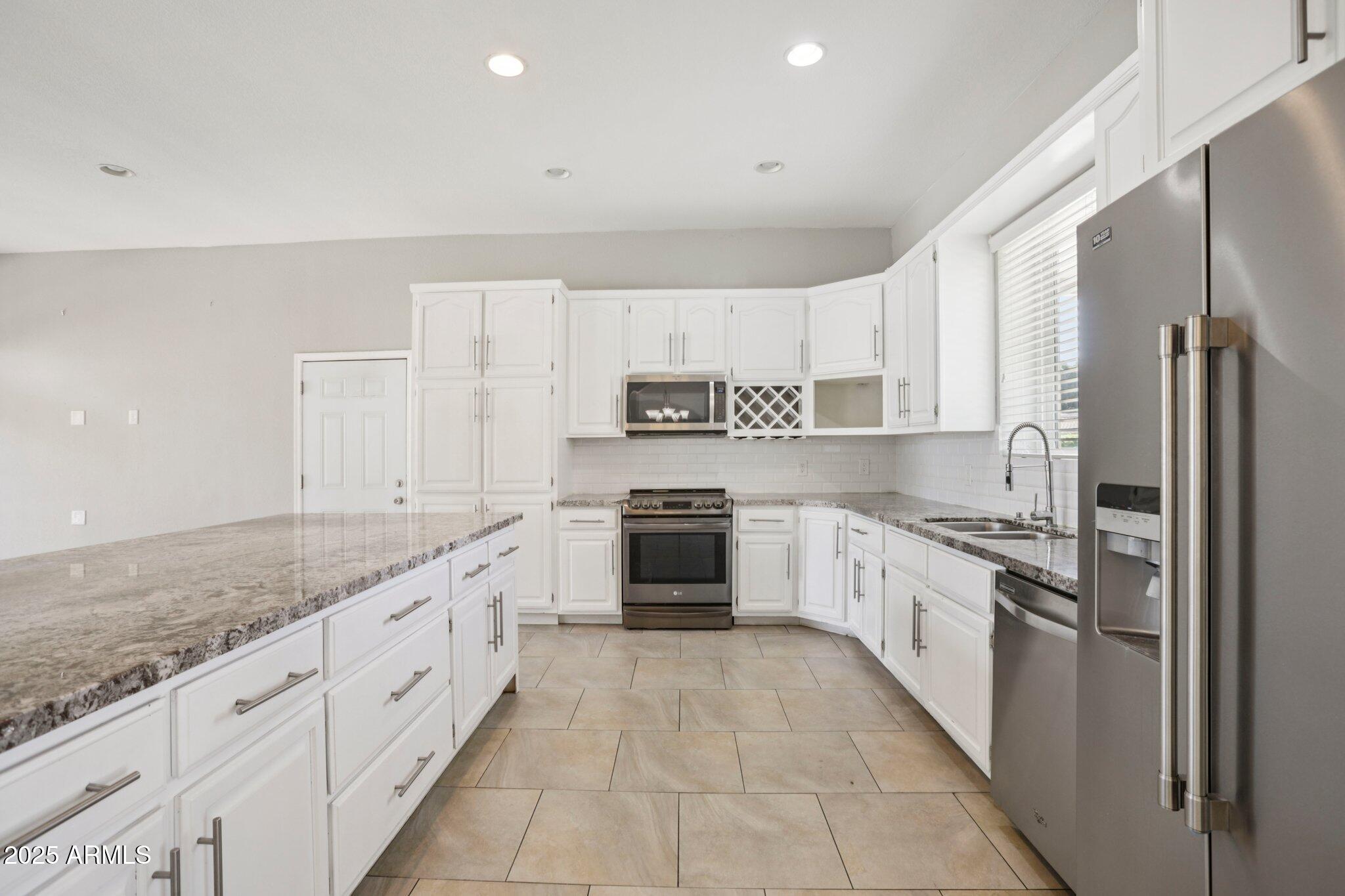 702 West Why Worry Lane Phoenix, AZ 85021 - Photo 7 of 46 a large kitchen with stainless steel appliances granite countertop a stove a sink and a refrigerator