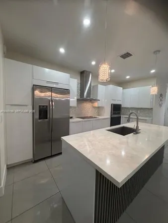 a kitchen with kitchen island sink and refrigerator