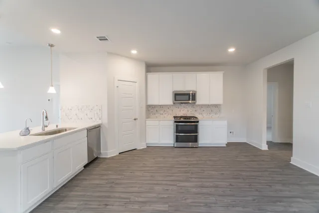 a view of a big room with wooden floor and a kitchen