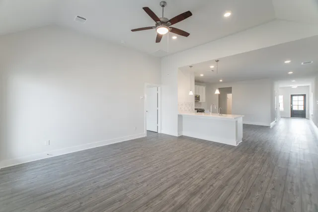 an empty room with wooden floor fan and windows