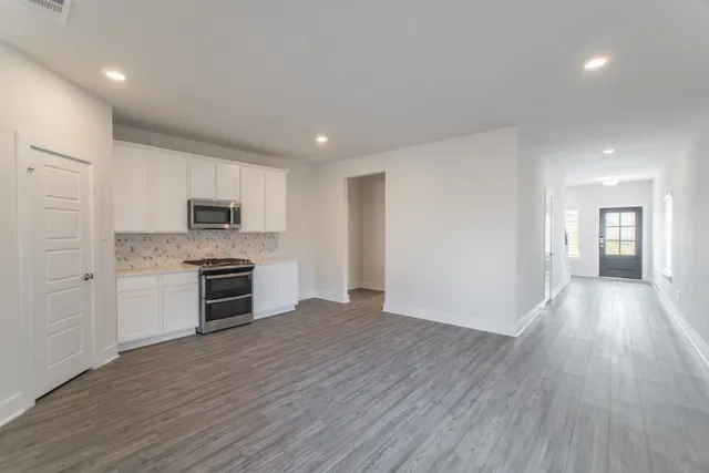 a large kitchen with stainless steel appliances a large counter top a stove and a refrigerator