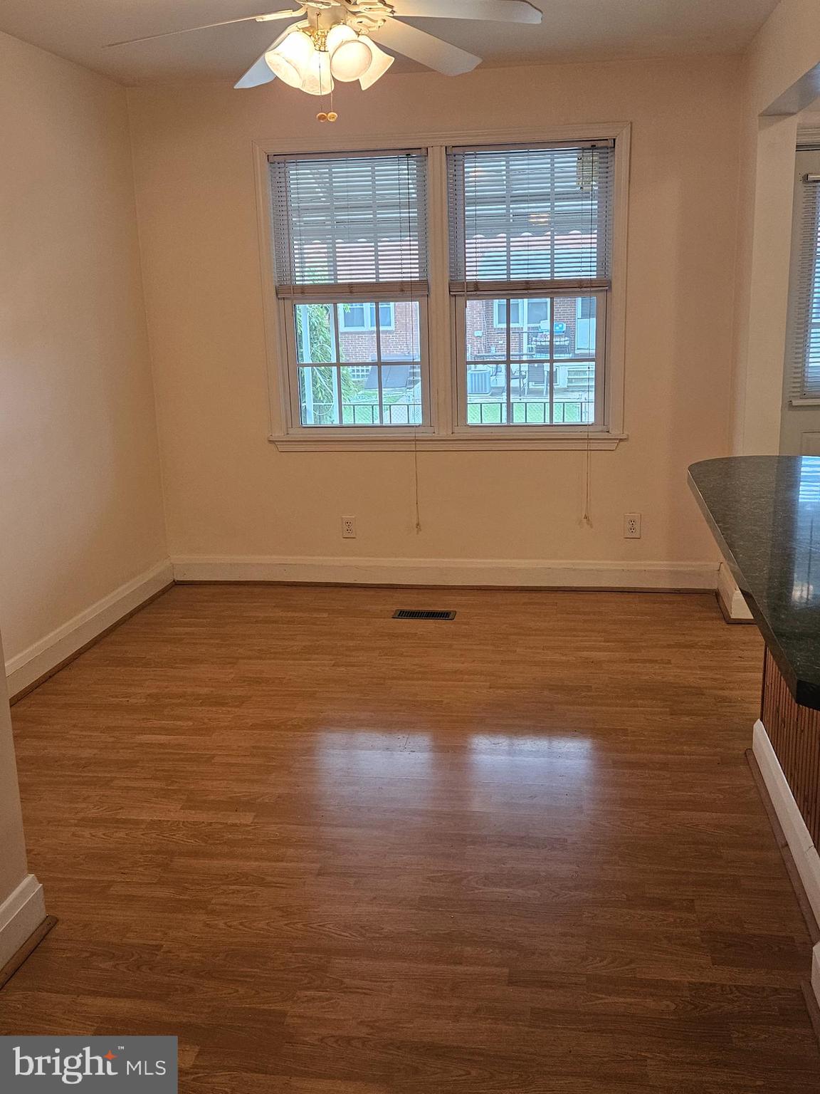 6907 Belclare Road Baltimore, MD 21222 - Photo 6 of 26 an empty room with wooden floor and windows