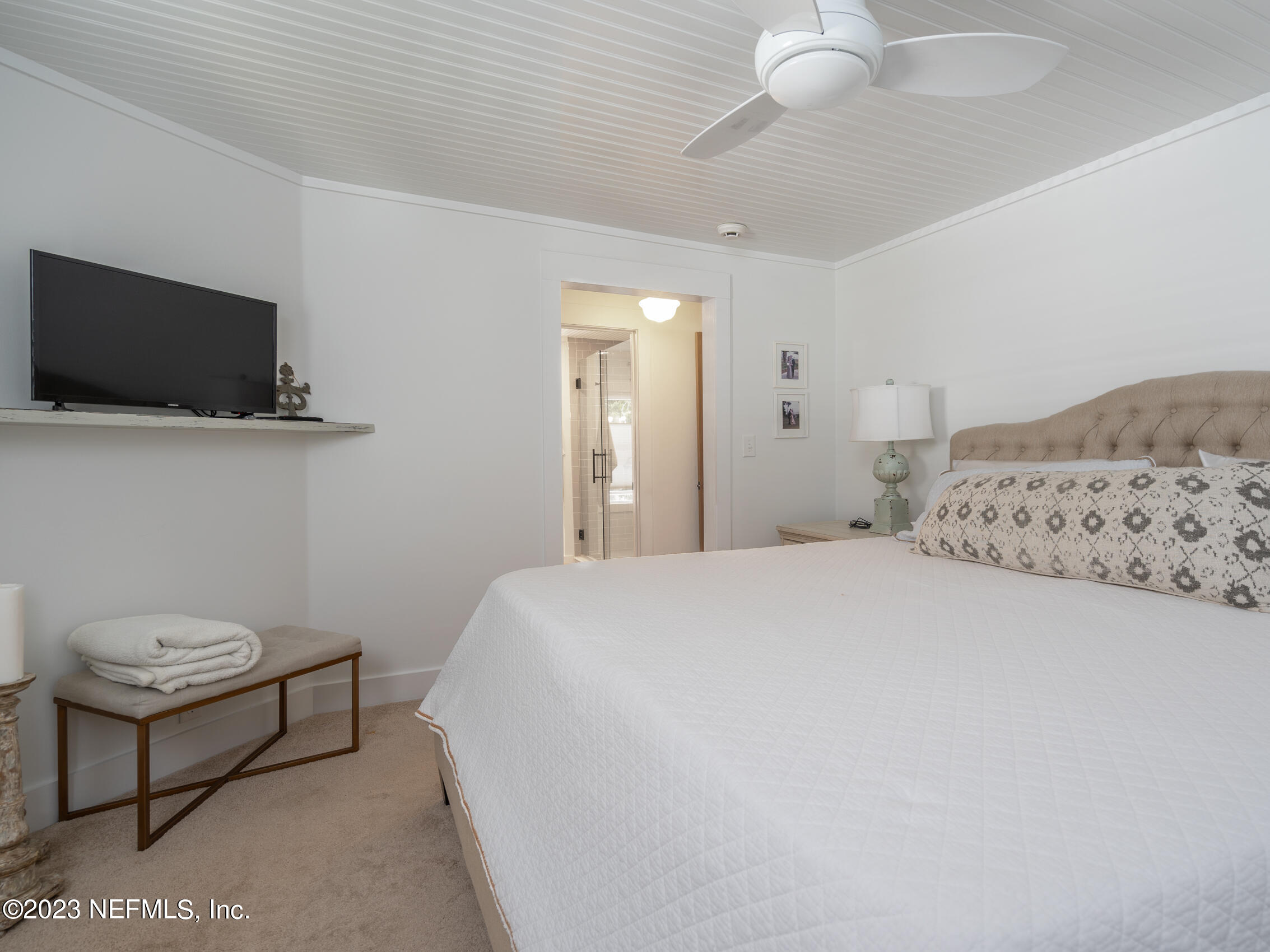 124 South 5th Street Fernandina Beach, FL 32034 - Photo 28 of 60 a bedroom with a bed a flat screen tv and a chandelier