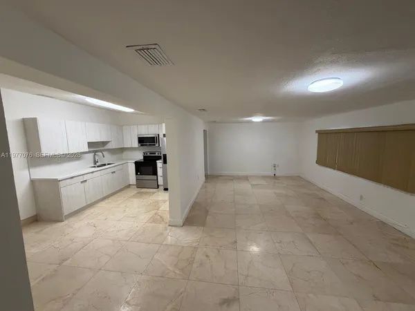 a view of a kitchen with a sink and dishwasher a refrigerator with white cabinets
