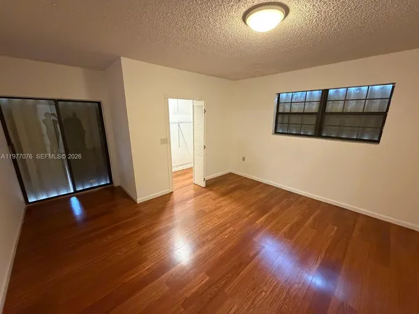 an empty room with wooden floor and windows
