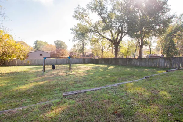 a view of yard with large tree and wooden fence