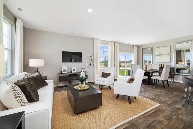 a living room with furniture flat screen tv and large windows