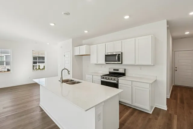 a kitchen with stainless steel appliances granite countertop a sink stove microwave and refrigerator