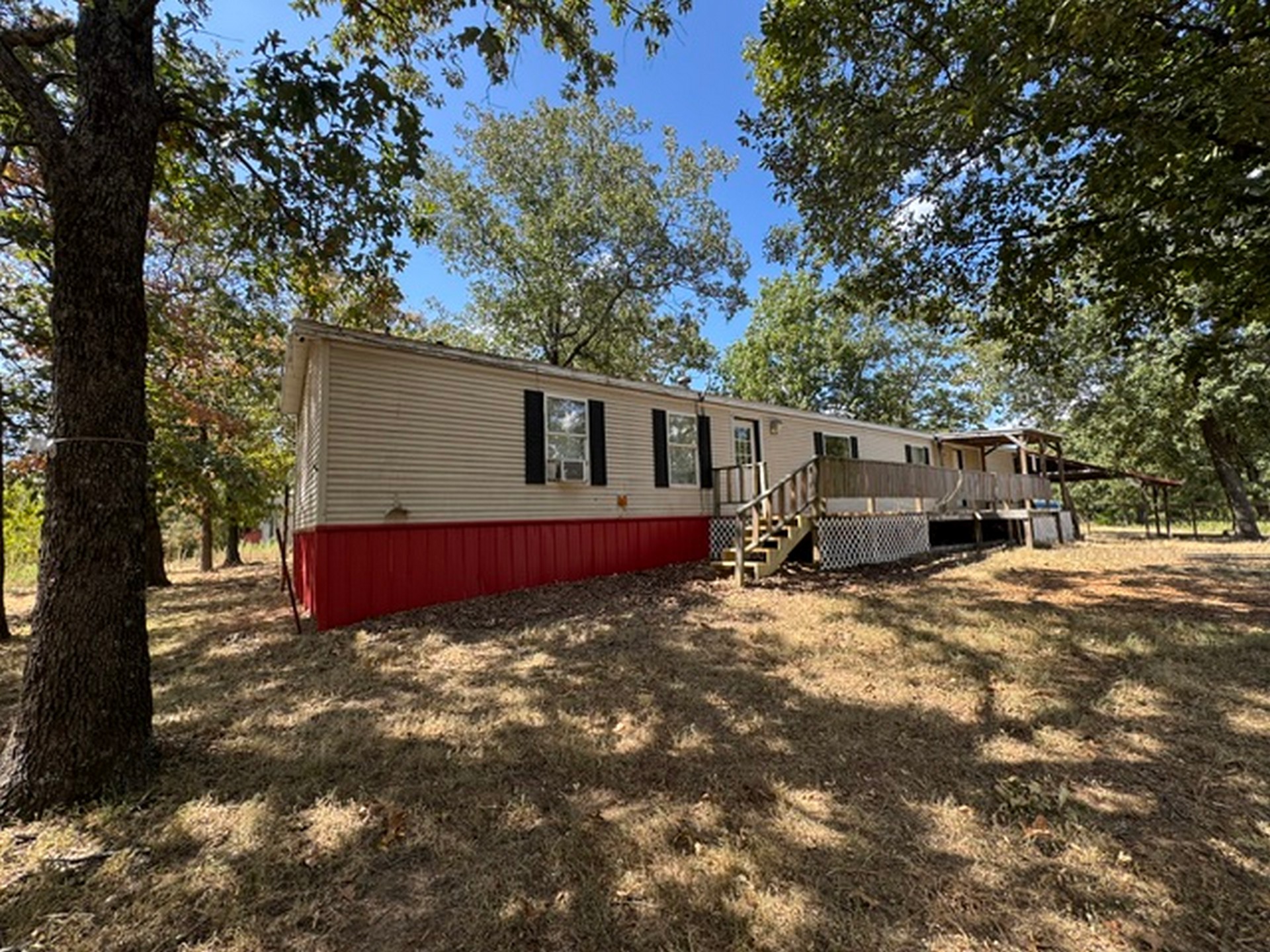 109558 South 4760 Road Muldrow, OK 74948 - Photo 6 of 22 Expansive wood deck with lattice skirting, featuring a covered portion and multiple entry points