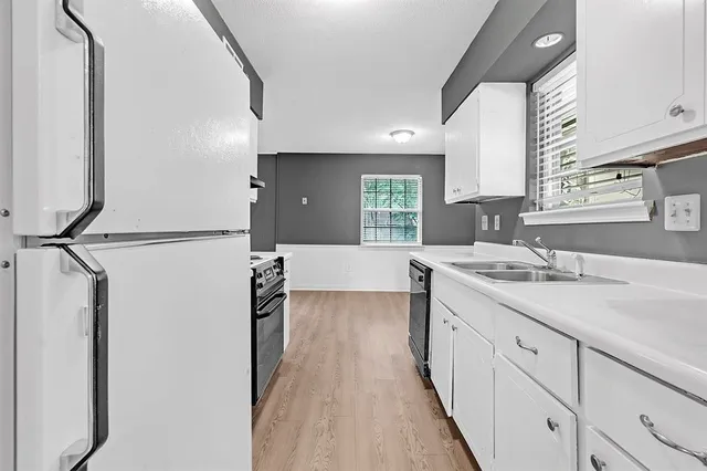 a large kitchen with a sink and a wooden floor