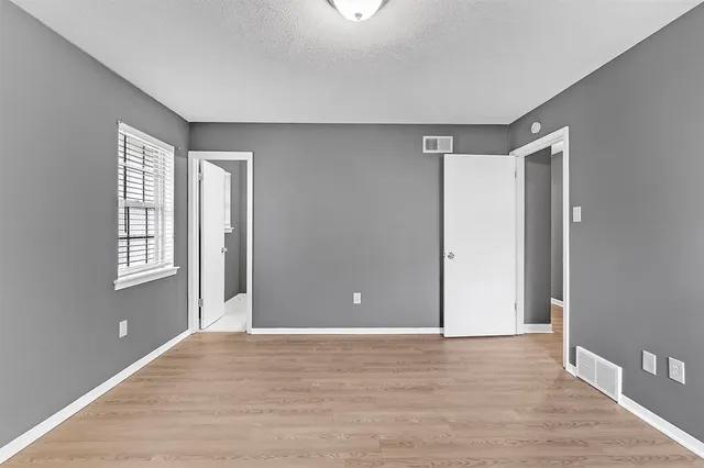 a view of an empty room with window and wooden floor